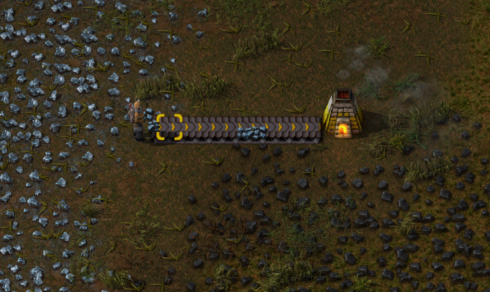 Factorio screenshot of player sending iron ore along a conveyor belt to a stone furnace